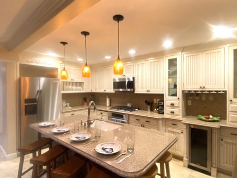 Kitchen with a large refrigerator, seating for four, gas stove, wine refrigerator, and regular and convection oven. Easy access to a patio with seating for four.