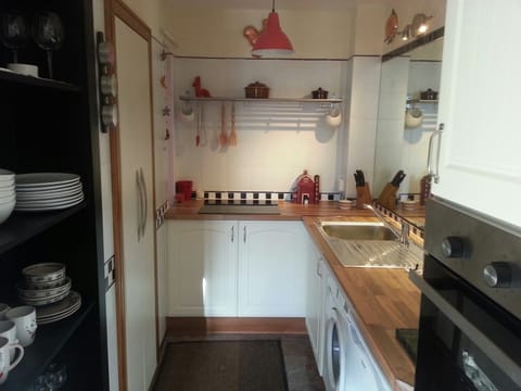 Kitchen shelves with pantry on left,  sink washing machine and wall oven