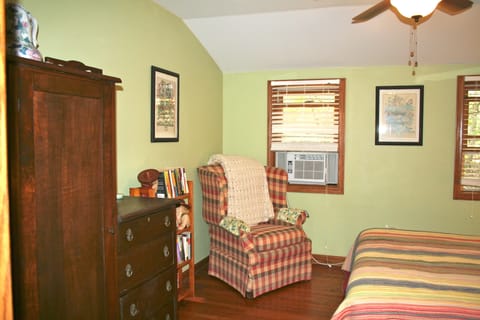 The bedroom is furnished with a queen bed, armoire, and comfortable seating.