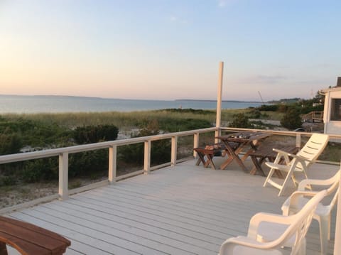 Deck view east. Round cedar table, benches, umbrella, chairs, picnic table