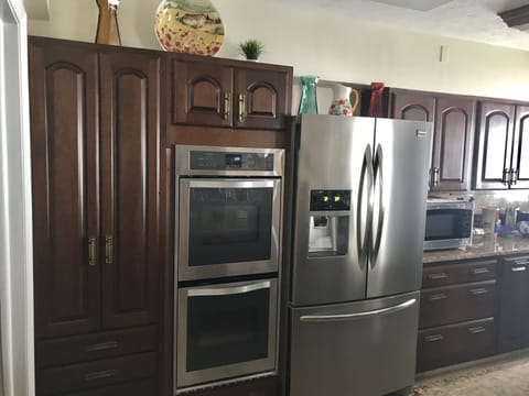 Kitchen with new stainless steel double oven and refrigerator.