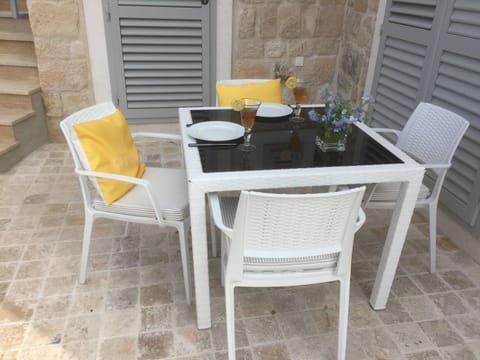 The dining table is at the far side of the L-shaped terrace, in the shade