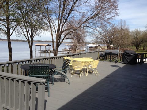 Deck with two tables and charcoal and gas grills.