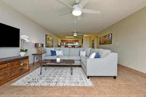 Living room with sectional sofa, coffee table, and tropical accents.