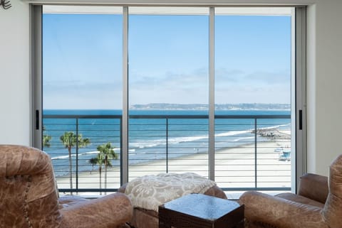 Sliding glass windows open to waves and ocean breeze
