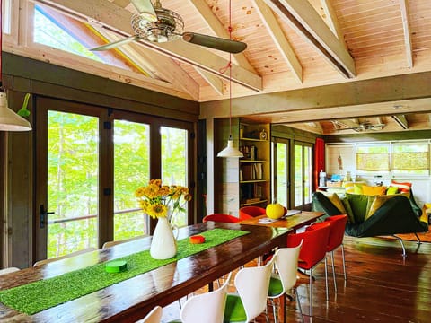 Dining room with wall of windows and doors framing peak fall color views.