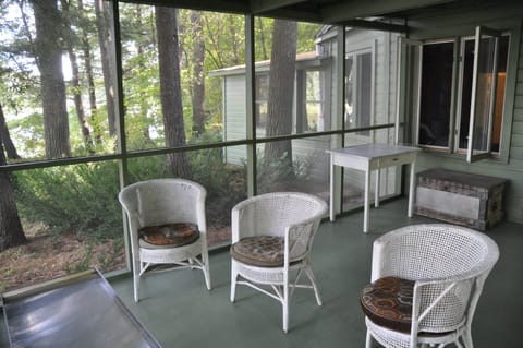 The screen porch, surrounded by pines, extends toward the river.