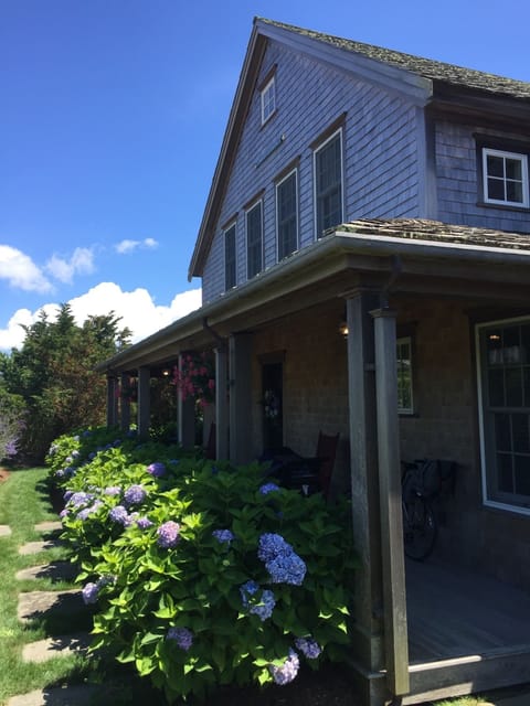 The front porch is covered and surrounded by hydrangea bushes