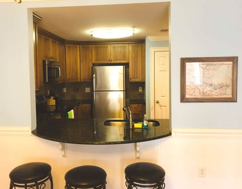Kitchen opens into living area with stools at the counter.