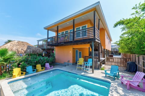 Modern beach house with private pool surrounded by vibrant tropical landscaping and cheerful outdoor seating.