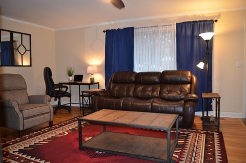 Great room with desk, a reclining arm chair, loveseat, and leather sofa.