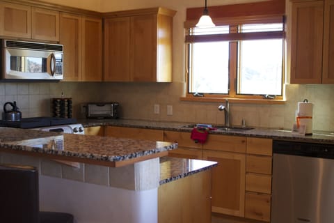Kitchen with granite countertops and fine appliances. Seating for 4 at bar.