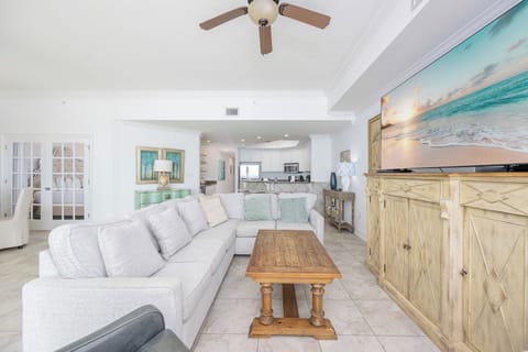 Living room featuring a plush sectional sofa with queen sleeper, rustic coffee table, and a large TV