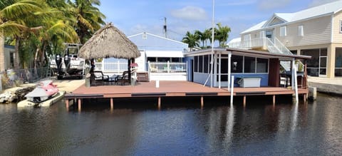 WATERFRONT VIEW OF HOUSE WITH LARGE DOCK!  TIKI AND  LARGE SCREENED IN PATIO . 
