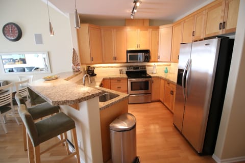This kitchen has an electric stove, microwave, dishwasher, and full fridge.