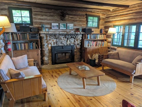 The living room with a stone fireplace and cozy spots to sit and read. 