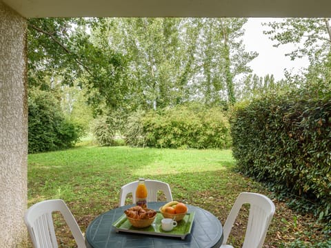 Enjoy serene outdoor moments on the cozy patio, surrounded by lush greenery and a delightful breakfast spread of pastries and fresh fruit.