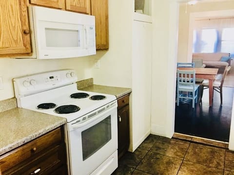 View of kitchen with microwave & oven with electric range, dishes fully stocked.