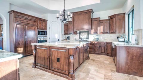 Gourmet kitchen with rich wood cabinetry, granite counters, and a large island.