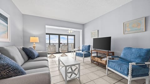 Gulf Tower 4C - Living area with a TV and a glass-enclosed balcony overlooking the Gulf.