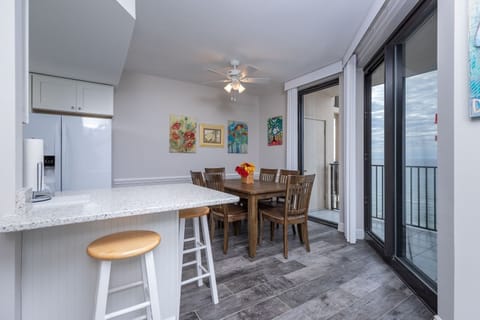 Gather around the wooden dining table, surrounded by colorful artwork and enjoying refreshing breezes from the balcony