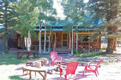 A rustic mountain cabin nestled among aspen and pine trees, with your own outdoor fire pit area surrounded by colorful Adirondack chairs—perfect for stargazing and s'mores.
