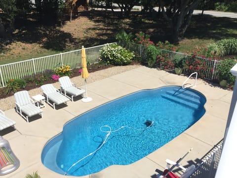 Pool with 4 lounge chairs and 2 umbrellas. 2 Adarondak chairs and side tables.