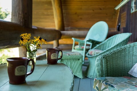 Balcony on back of log cabin with wicker furniture
