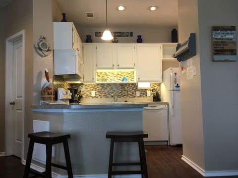 Newly updated kitchen with glass backsplash and under cabinet lighting.