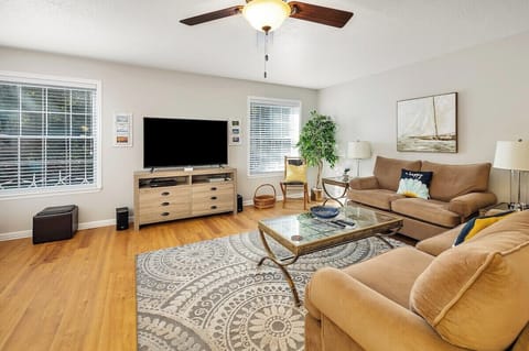 Living room with tan sofa, TV, and wood floors