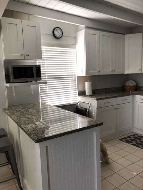 Bar stools at kitchen island with microwave.
