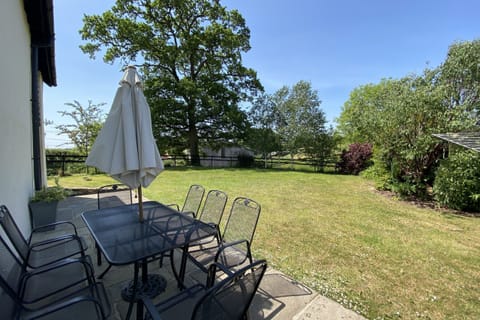 The terrace with garden furniture and barbecue and lawned area with dog-proof fencing