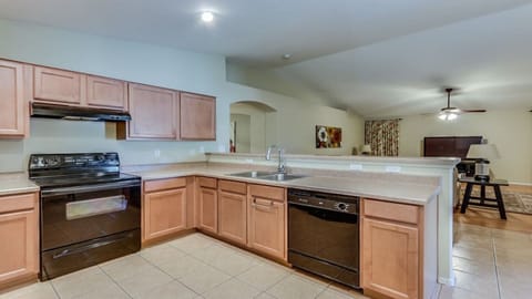 Kitchen with vaulted ceilings that looks into family room with television.