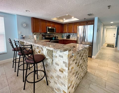 Another view of the kitchen with bar stool seating, plus view of - Another view of the kitchen with bar stool seating, plus view of the front entry door.