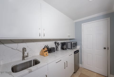 Kitchenette with fridge, microwave, coffee maker, toaster, blender, & sink.