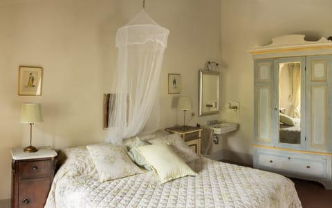 Large double bedroom with hand basin & antique Tuscan beside cupboards.
