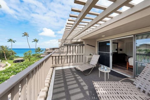 Spacious lanai with pergola-style cover, tropical greenery, and comfortable seating for relaxing outdoors.