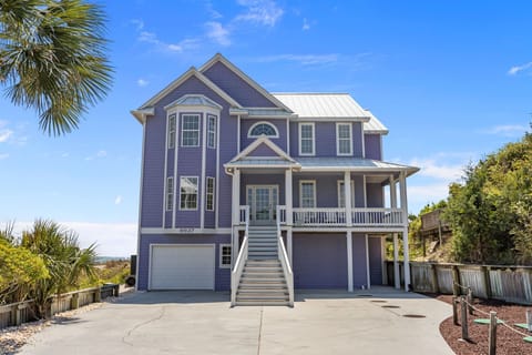 Charming coastal home with wraparound porch and tropical landscaping creates the perfect beach getaway setting.
