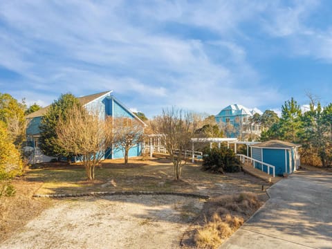 Charming coastal property featuring distinctive blue architecture nestled among mature trees and landscaped grounds with convenient parking access.