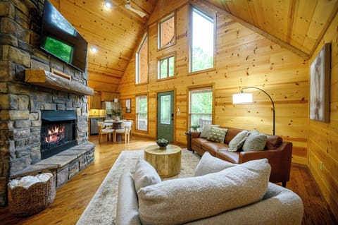 Cozy up in your rustic living room where warm wood walls and a crackling stone fireplace create the perfect mountain retreat ambiance.