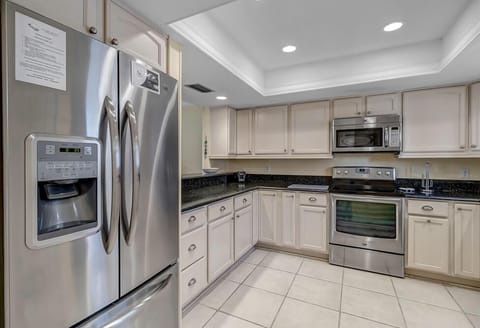 - Stay fully stocked with this spacious stainless steel fridge beside modern appliances and deep counters
- Neutral tones and tile flooring add warmth to this practical layout
- Open design makes cooking and snacking easy for any group size