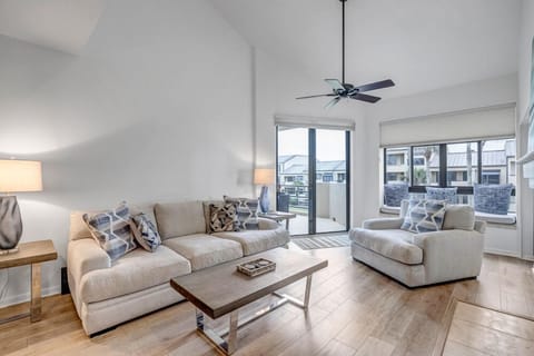 - Bright living area with neutral toned sofas and cozy accent pillows throughout
- Ceiling fan, tall windows, and a sliding door invite breezes and natural light
- Stylish, open space perfect for lounging after beach or pool days nearby