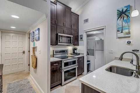 - Compact yet stylish kitchen with stainless steel appliances and quartz counters
- Dark wood cabinetry offers contrast and plenty of storage space for essentials
- Convenient layout with open access to laundry and view into main living space
