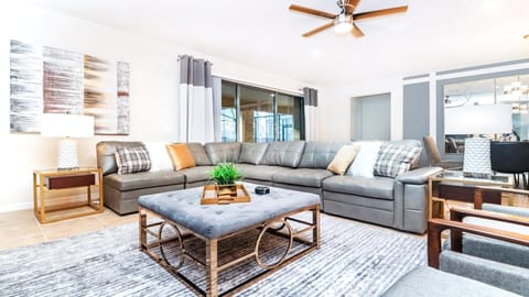 Modern living room with spacious sectional sofa, large TV, chic blue accents, and stylish decor.