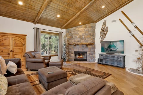Cozy mountain living room with a stone fireplace, comfy seating, and smart TV—perfect for relaxing evenings, movie nights, and warm cabin vibes after outdoor adventures.