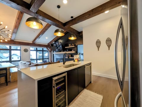 Your gourmet kitchen awaits with gleaming countertops, wine fridge, modern appliances, and rustic beams