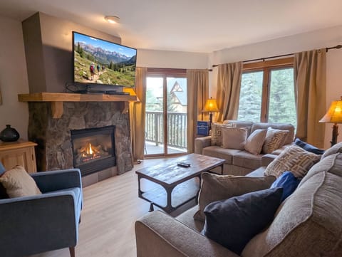 Unwind on plush couches beside your glowing fireplace, surrounded by warm wood tones and natural light streaming through the windows. Your cozy mountain retreat awaits, blending rustic charm with modern comfort.