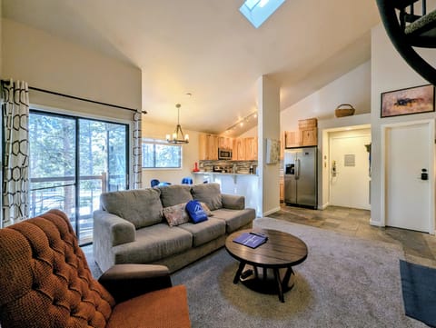 Your spacious retreat flows seamlessly from cozy living area to modern kitchen, with natural light streaming through the skylight above.