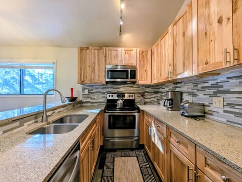 Cook up memorable meals in your spacious kitchen featuring warm wood cabinets, granite countertops, and stainless steel appliances with forest views.