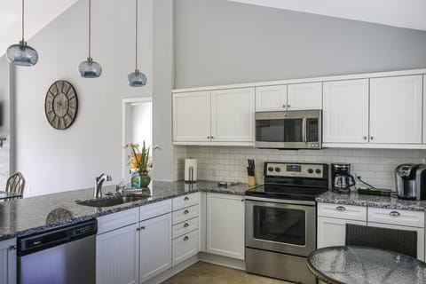 Beaming white cabinetry; Stainless steel appliances